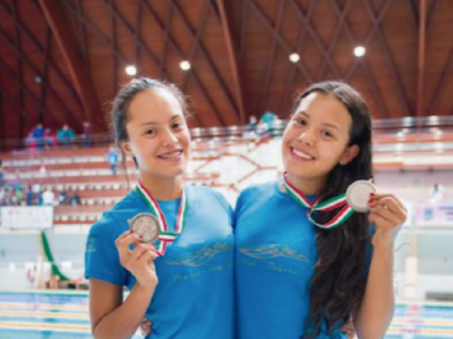 Deportistas de natación con aletas sostienen sus medallas